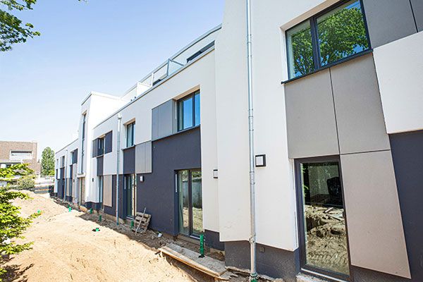 Weiß verputzte Neubaufassade mit hellgrauen und anthrazitfarbenen Fassadenplatten, aus spitzem Winkel aufgenommen